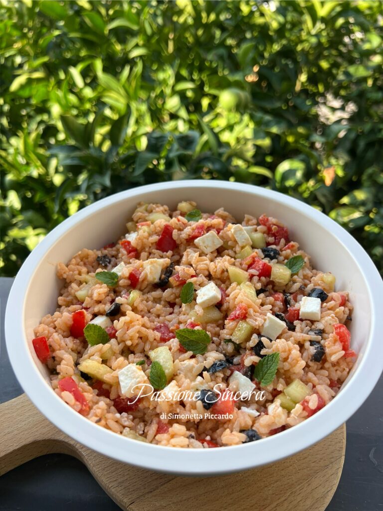Insalata di riso alla greca con pomodorini, cetrioli, feta, olive nere e basilico o menta