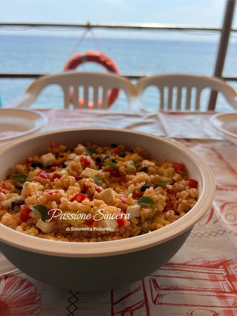 Insalata di riso alla greca con pomodorini, cetrioli, feta, olive nere e basilico o menta